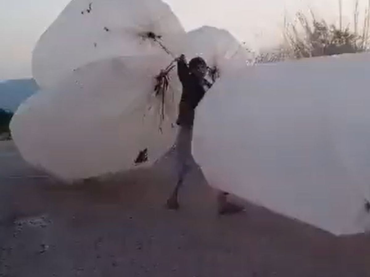 A boy carries plastic bags filled with cooking gas in Pakistan