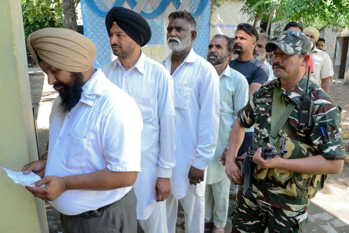 A central force personnel stands guard as voters queue up to cast ballots in India's general elections 2019