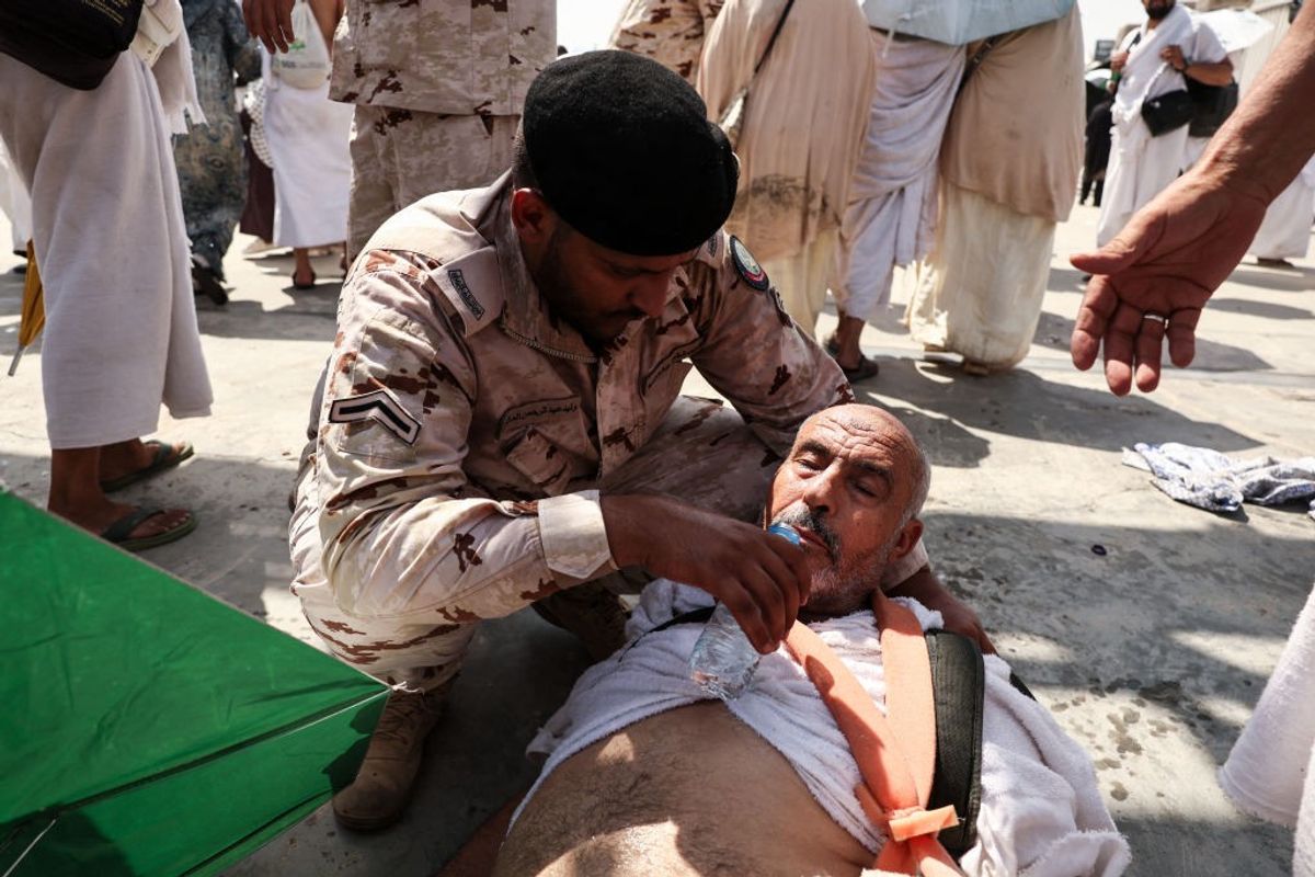 A man affected by the scorching heat is helped by a member of the Saudi security