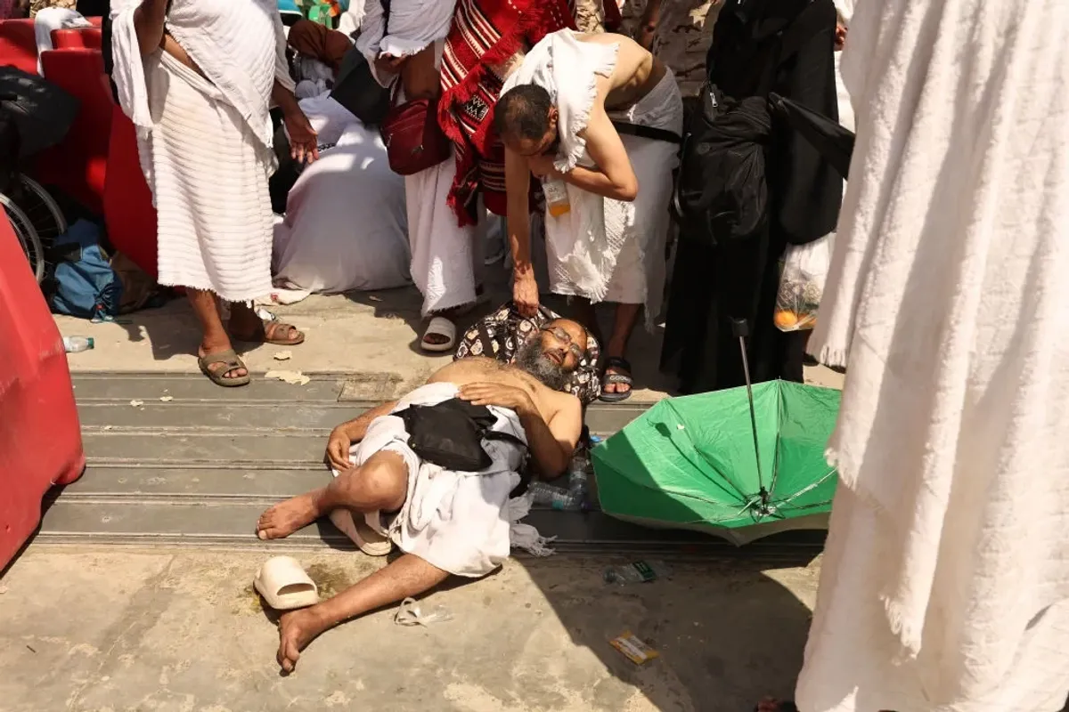 A man affected by the scorching heat is helped by another as Muslim pilgrims arrive in Saudi for Hajj.