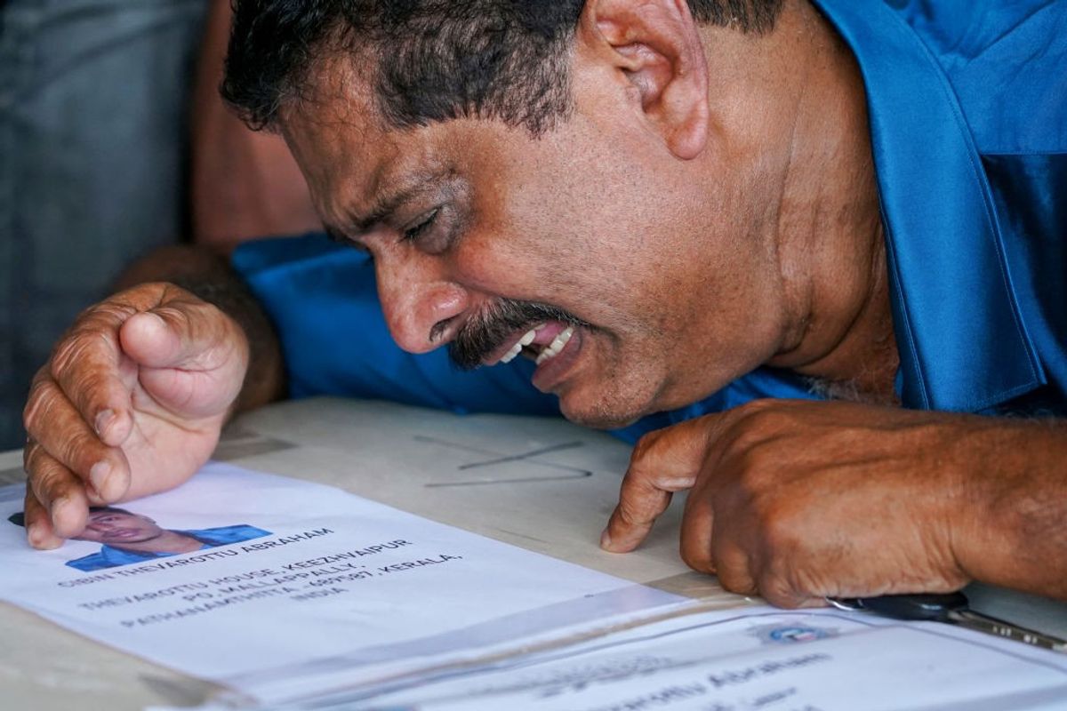 A man mourns the death of one of his relatives who died in the June 12 fire in Kuwait after his coffin arrived on an Indian Air Force plane from Kuwait at the Cochin International Airport in Kochi in the southern Indian state of Kerala