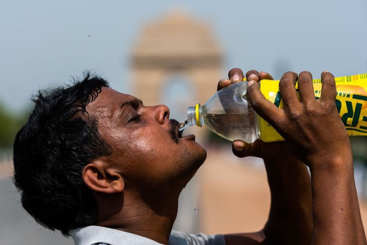 A man quenches his thirst from a bottle in intense heat in New Delhi, India