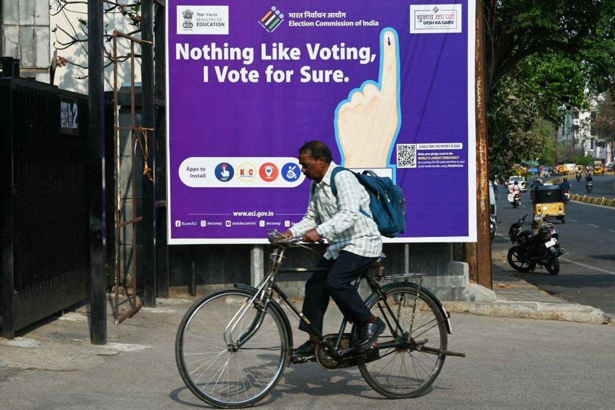 A man rides past an election awareness poster displayed along a street ahead of India's upcoming general elections, in Hyderabad in the southern state of Telangana