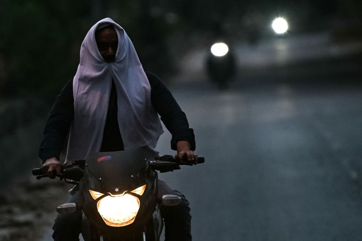 A man riding a motorcycle on a hot evening in Delhi, India.