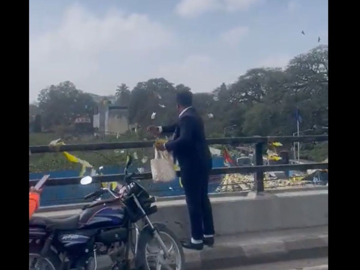 A man throws currency notes from the top of a flyover at a busy market area in the Indian city of Bengaluru
