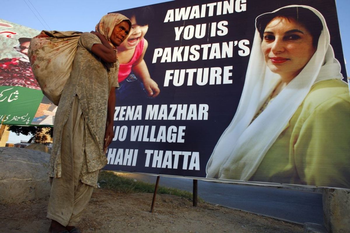 A Pakistani beggar walks by a poster of former Pakistani prime minister Benazir Bhutto in Karachi, Pakistan