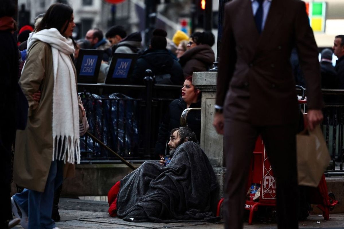 A rough sleeper sits outside Oxford Circus tube station, in central London, UK