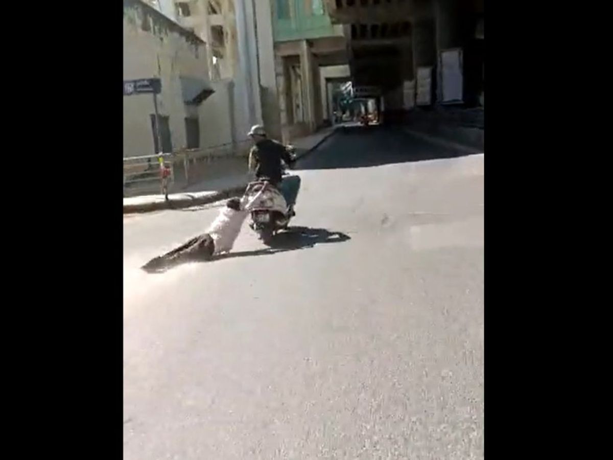 A scooterist drags an elderly man on a busy road in Bengaluru, India