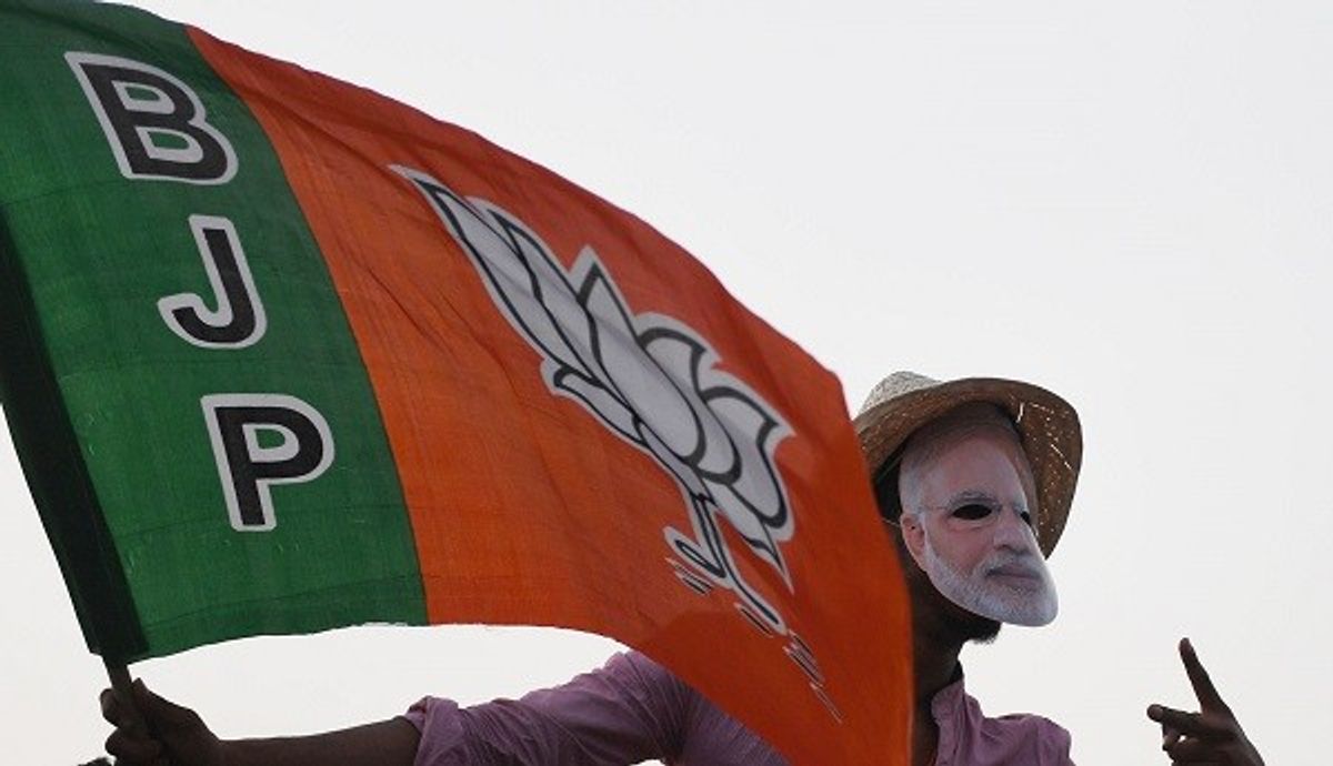 A supporter of India's ruling BJP with its flag and a mask of prime minister Narendra Modi
