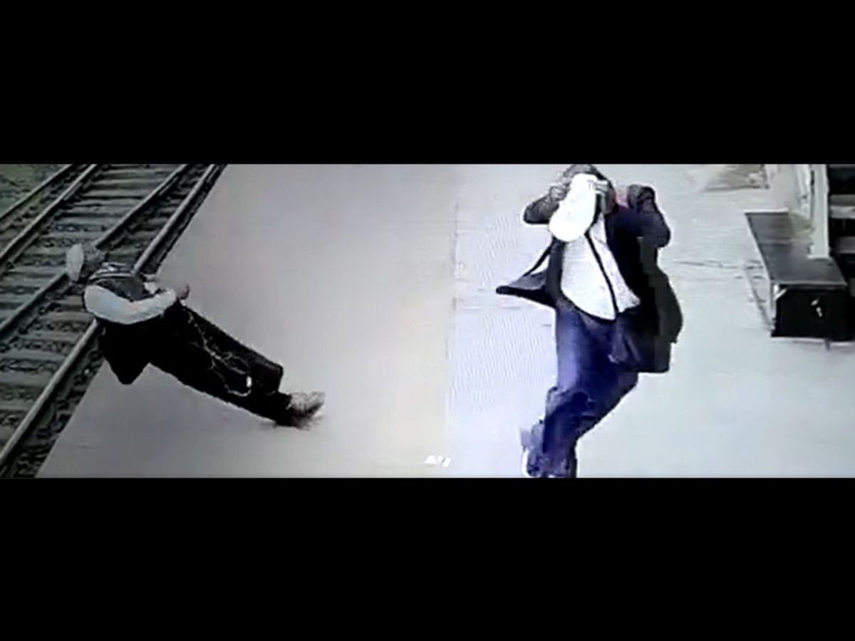A ticket examiner of the Indian Railways (L) collapses after a livewire fell on him from above on the platform of Kharagpur railway station in West Bengal, India.