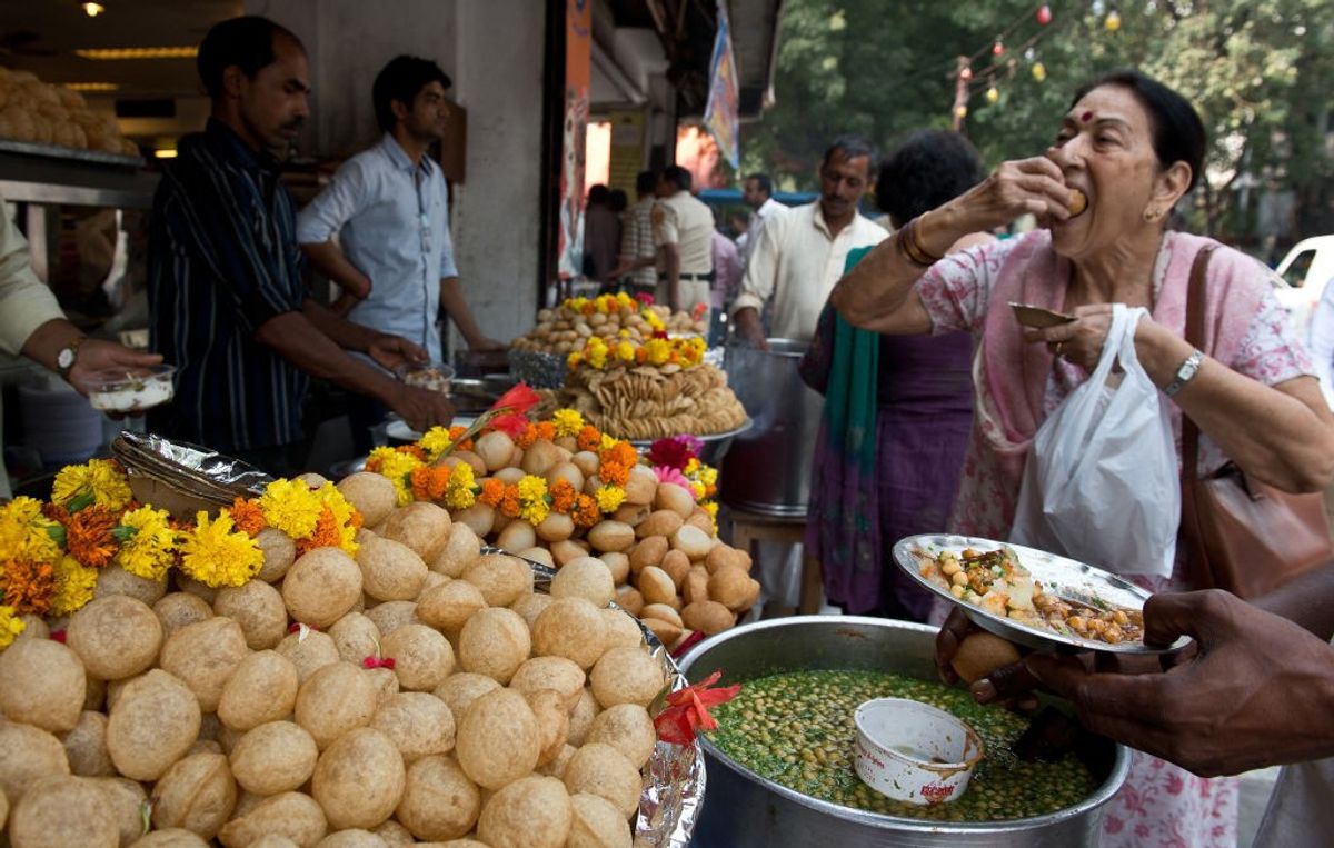 A woman in New Delhi, India, eats goalgappas at a roadside snack shop.