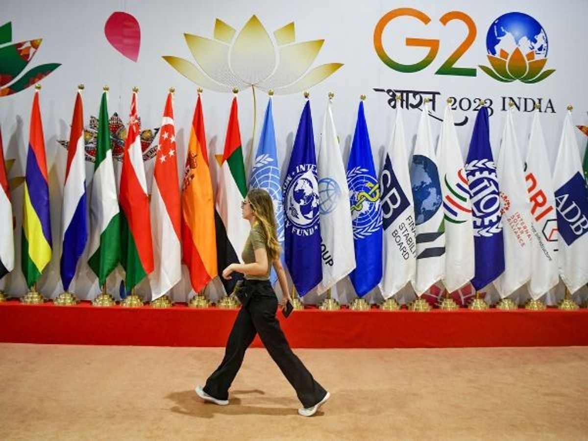 A woman passes by flags of participant countries during G20 summit, at International Media Center of Pragati Maidan in New Delhi on Friday, September 8,