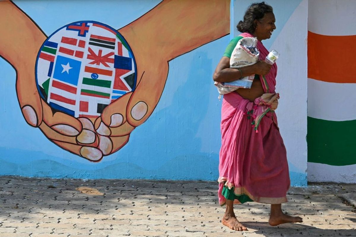 A woman walks past a wall mural of the G20 summit logo along a street in Visakhapatnam in the south-eastern Indian state of Andhra Pradesh