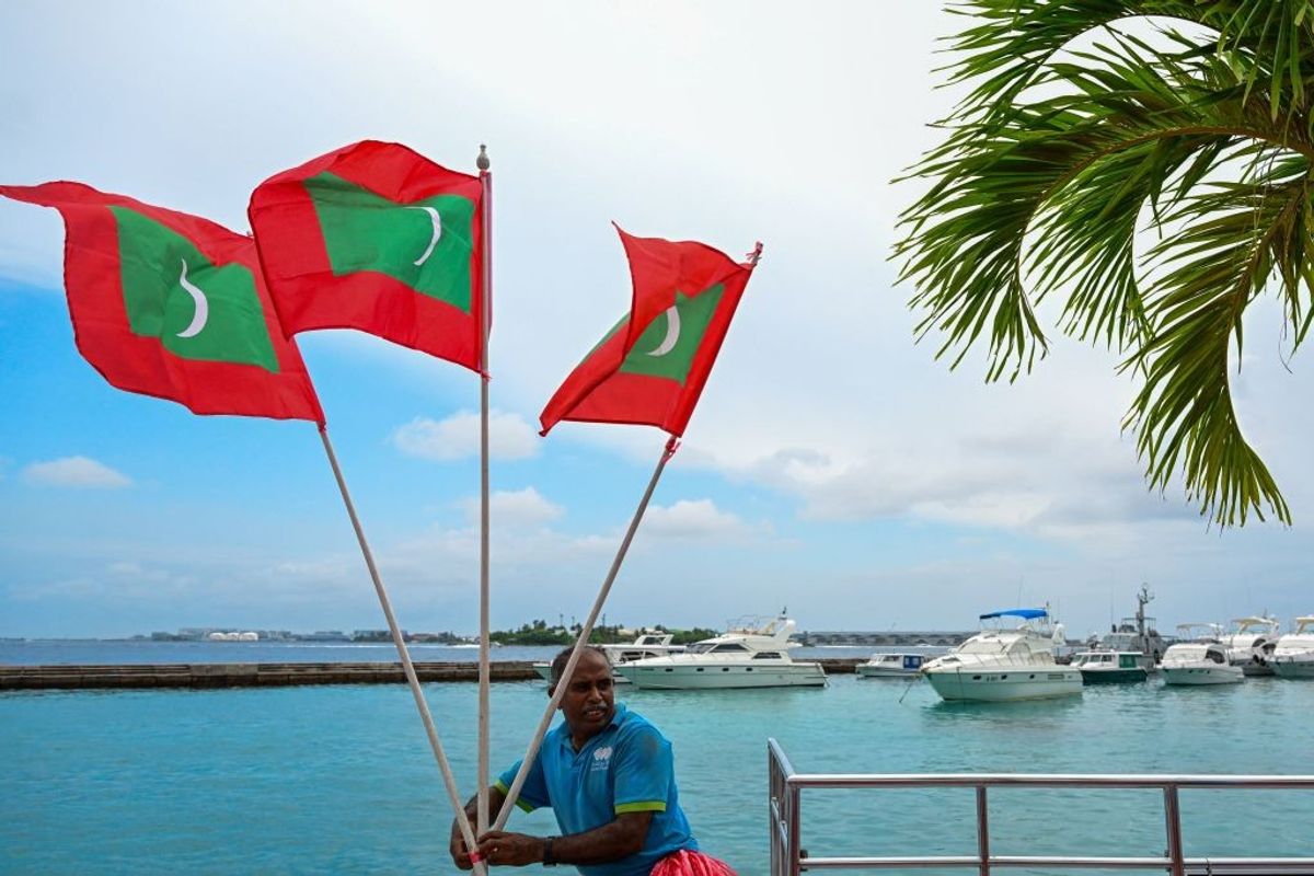 A worker carries national flags of the Maldives in Male.
