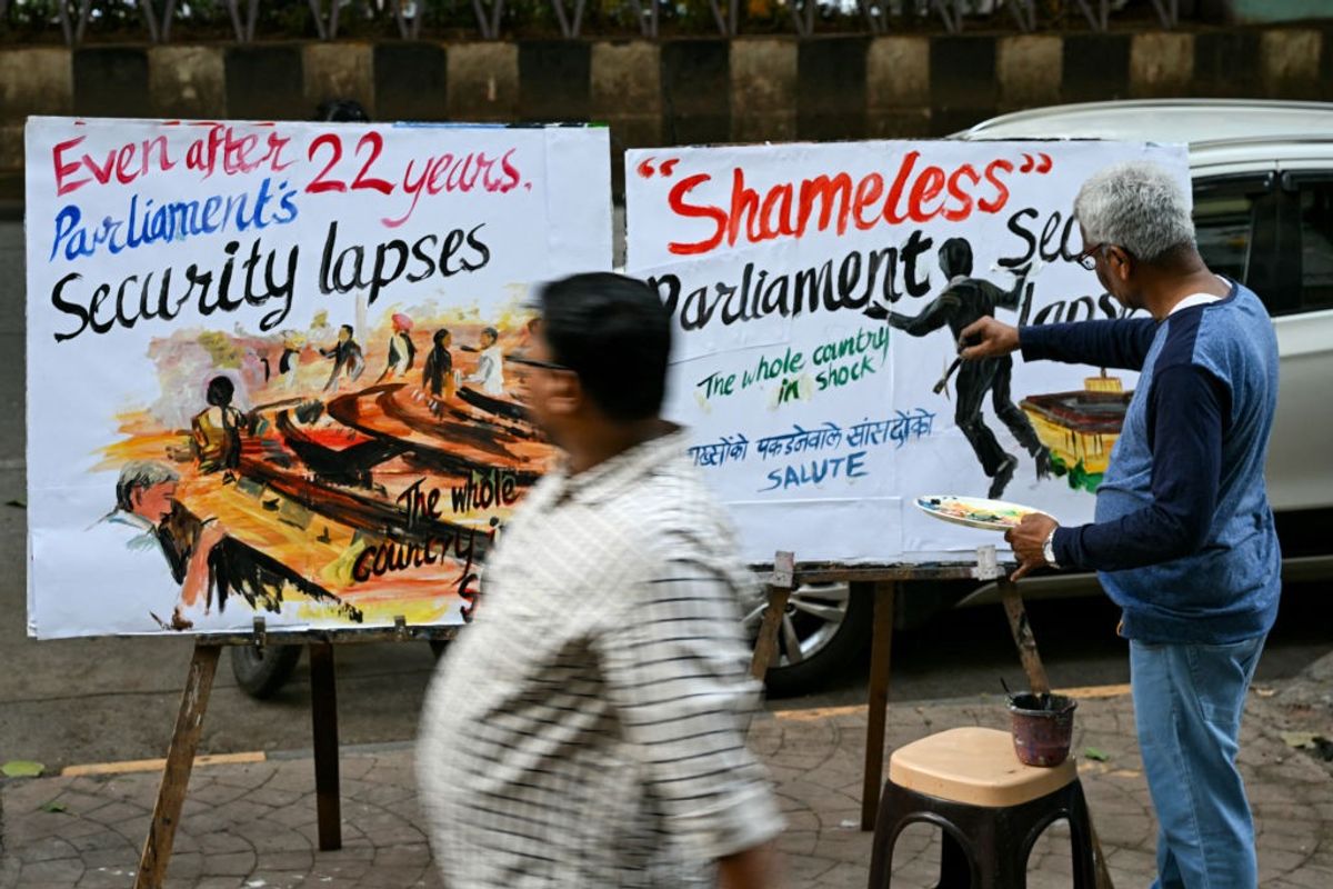 An art school teacher works on a painting along a pavement in Mumbai on December 13, 2023, depicting the security breach inside the lower house Lok Sabha in the capital, New Delhi.