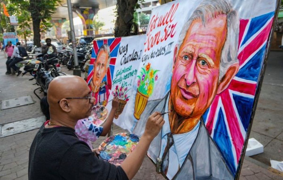 An artist gives finishing touches to a painting of King Charles III