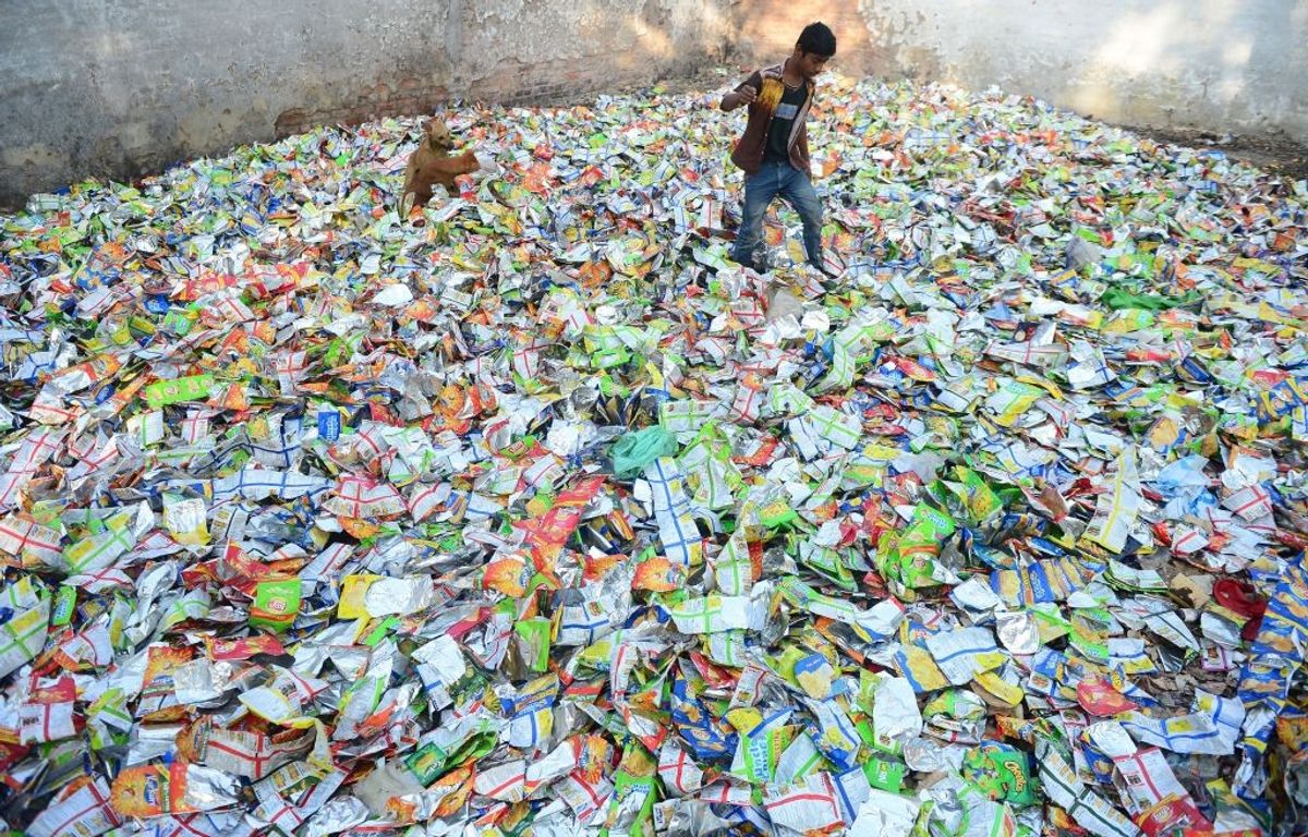 An Indian boy walks amid a heap of polythene packets in Prayagraj in the northern state of Uttar Pradesh