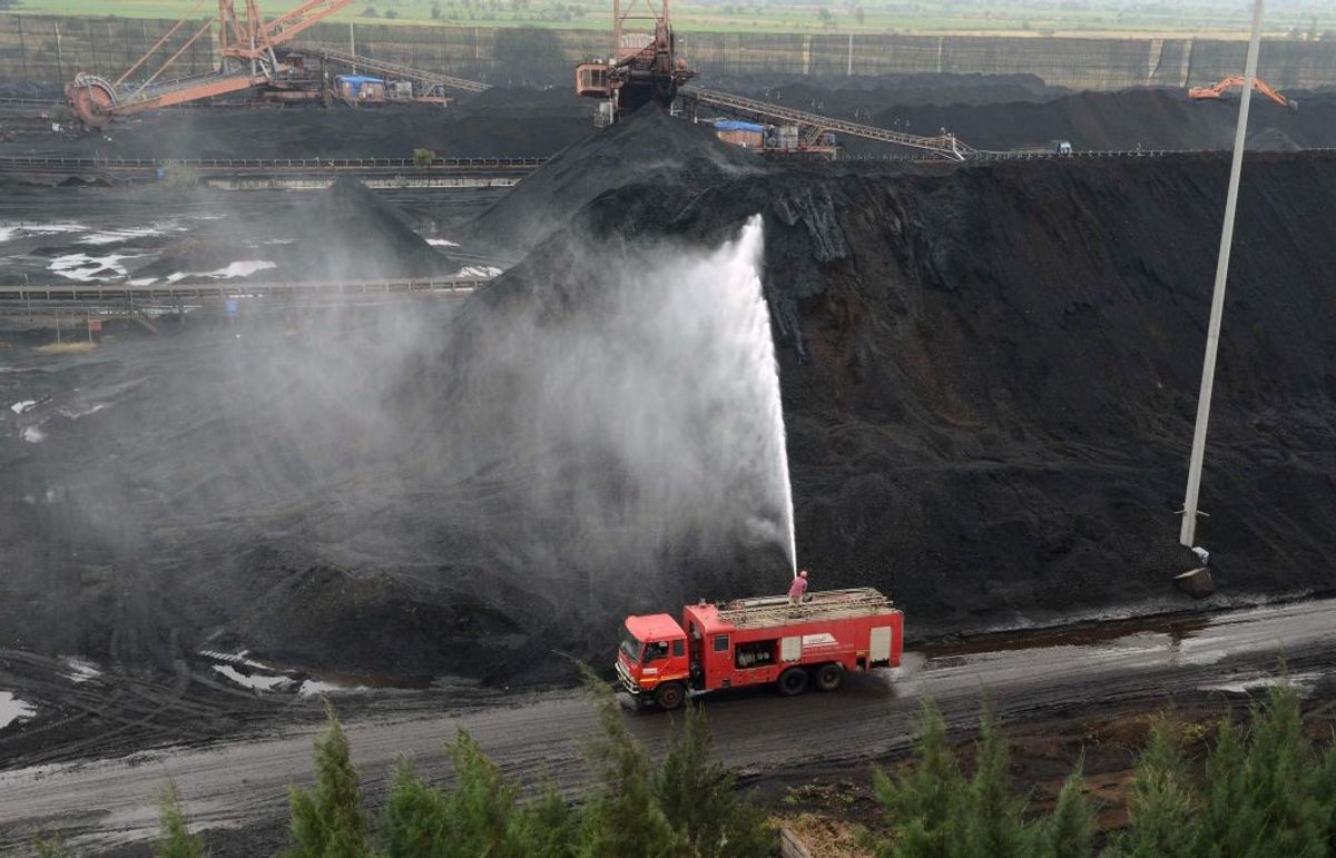 An Indian fire-fighter cools hot coal at a stockyard at a coal-fired thermal power plant belonging to Essar Power in Salaya, some 400km from Ahmedabad in the western state of Gujarat