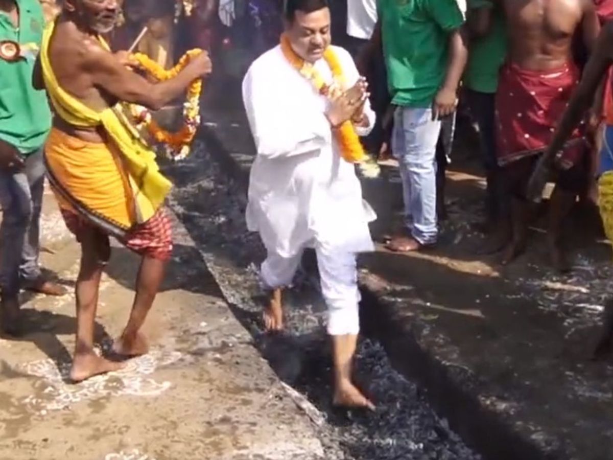Bharatiya Janata Party (BJP) leader Sambit Patra (in white) runs over a burning coal bed during a festival in the Indian state of Odisha
