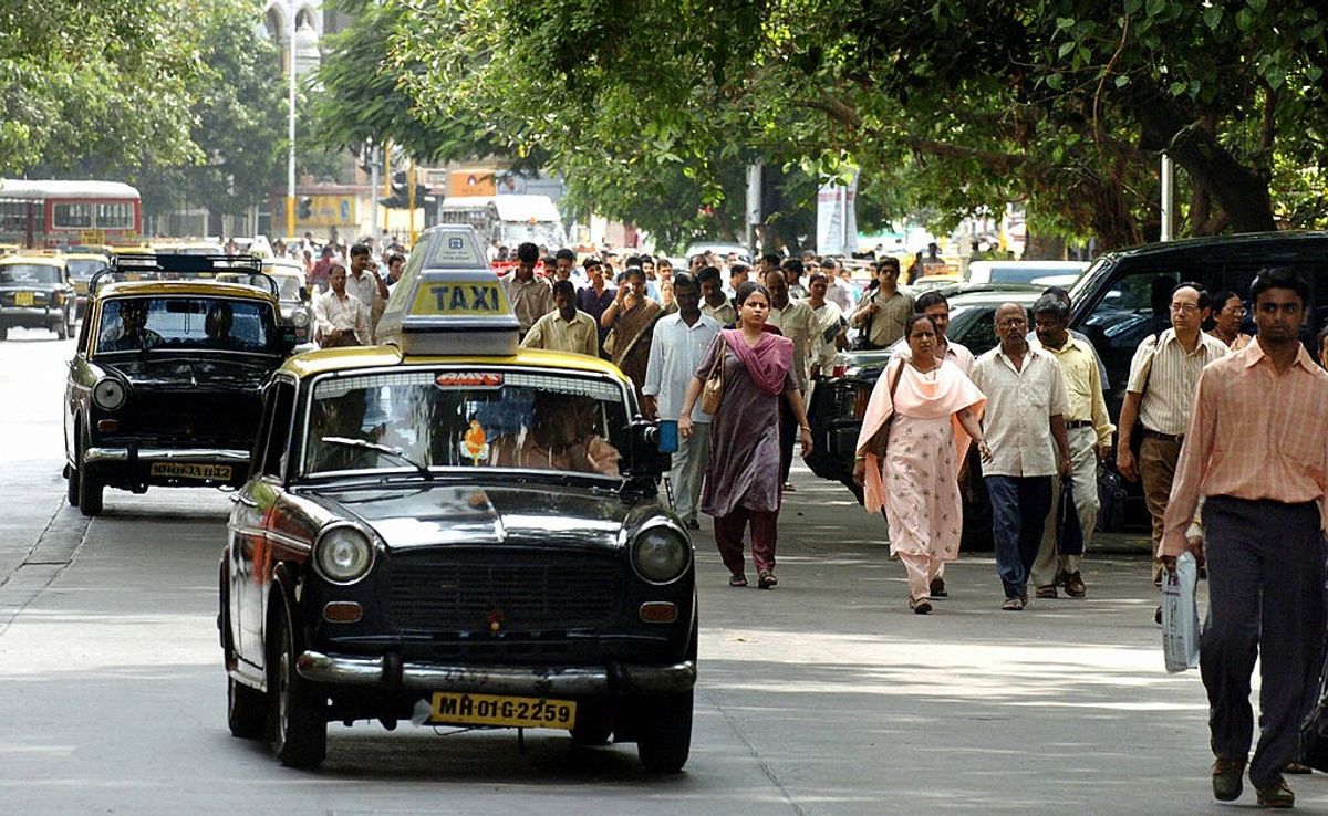 Commuters walk alongside Premier Padmini 'kaali-peeli' taxis