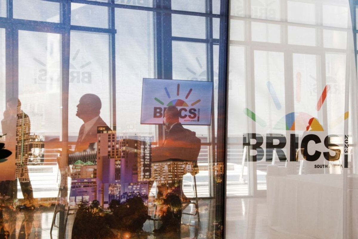 Delegates walk past the logos of the BRICS summit during the 2023 BRICS Summit at the Sandton Convention Centre in Johannesburg, South Africa,