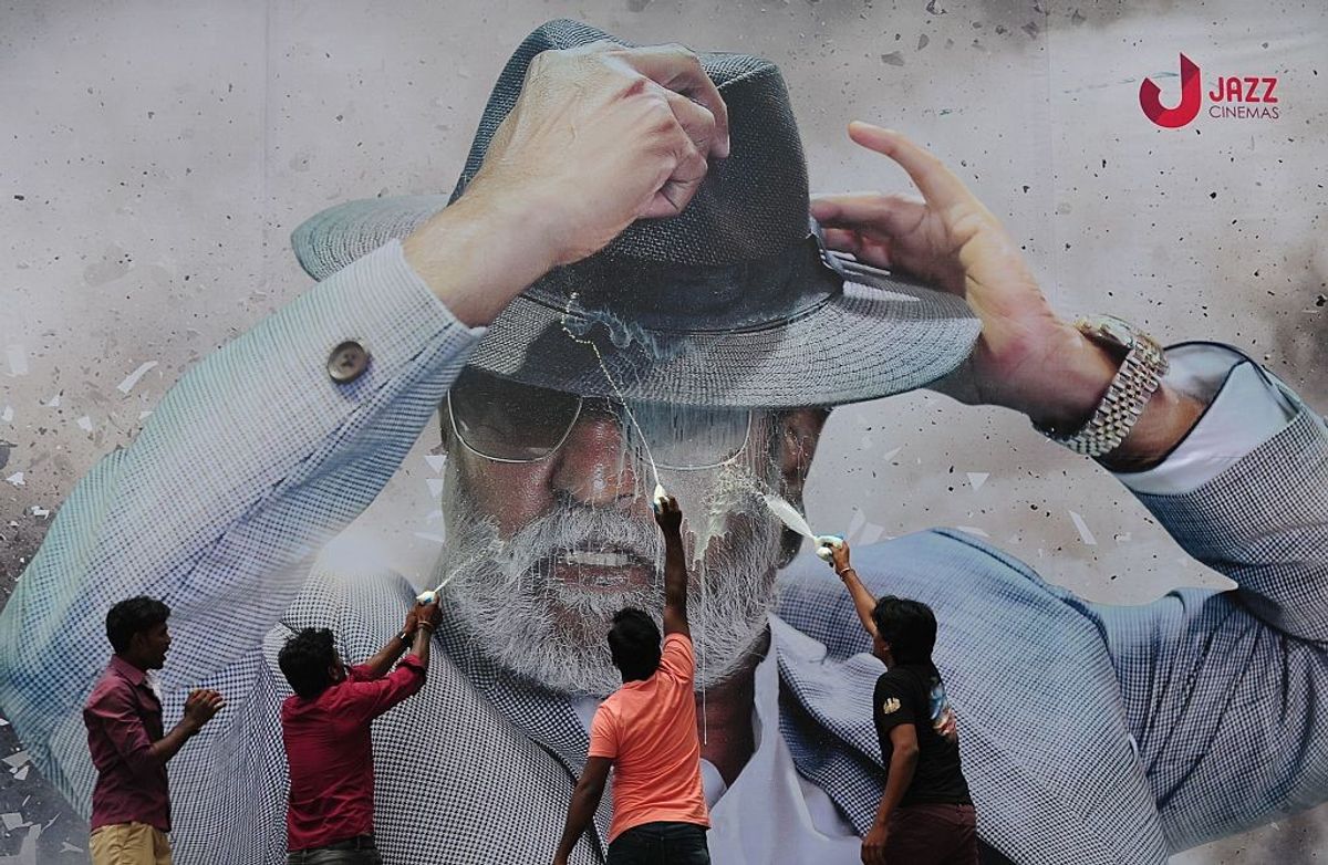 Fans spray milk on a poster of south Indian film actor Rajinikanth