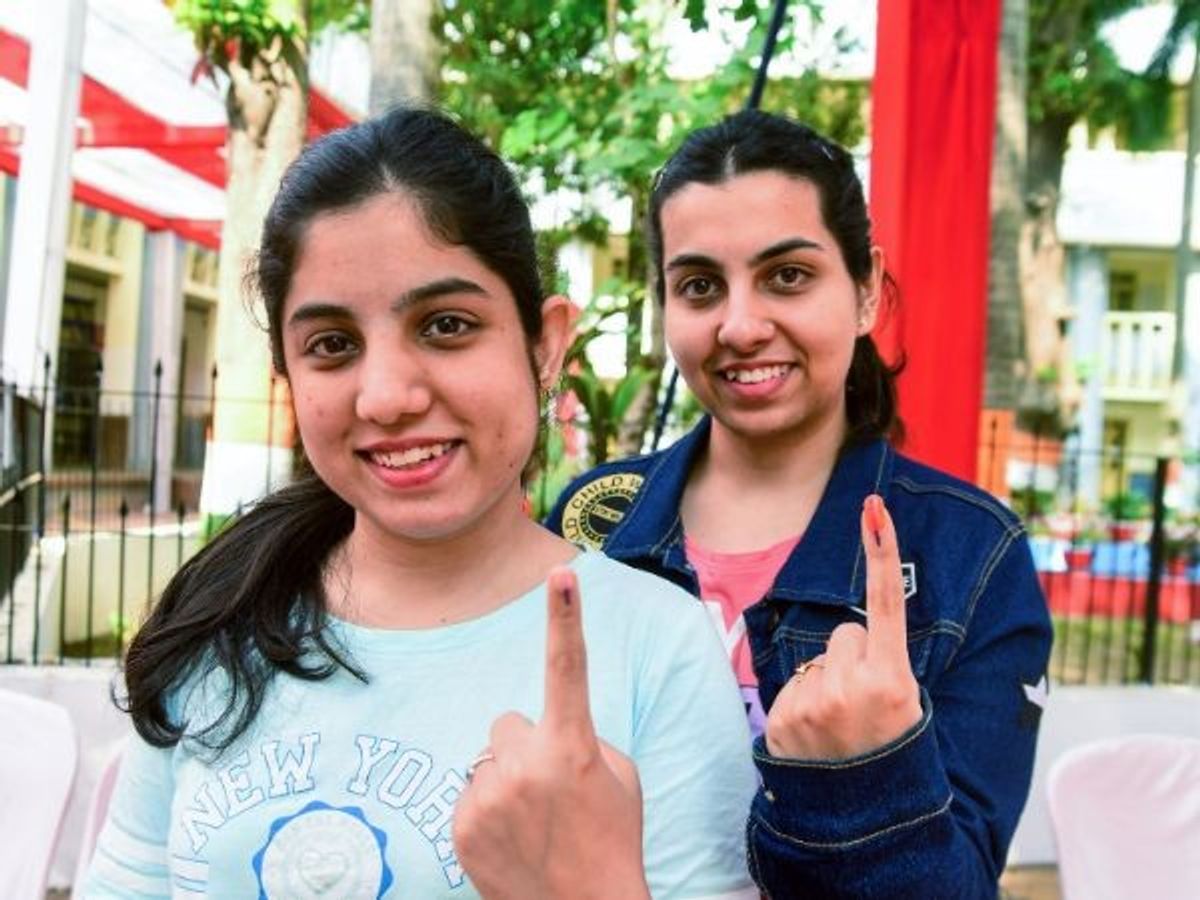 First-time voters and twin sisters Astha Pahwa (in front) along with Abha Pahwa, show ink marks on their fingers after casting votes during Madhya Pradesh assembly election 2023