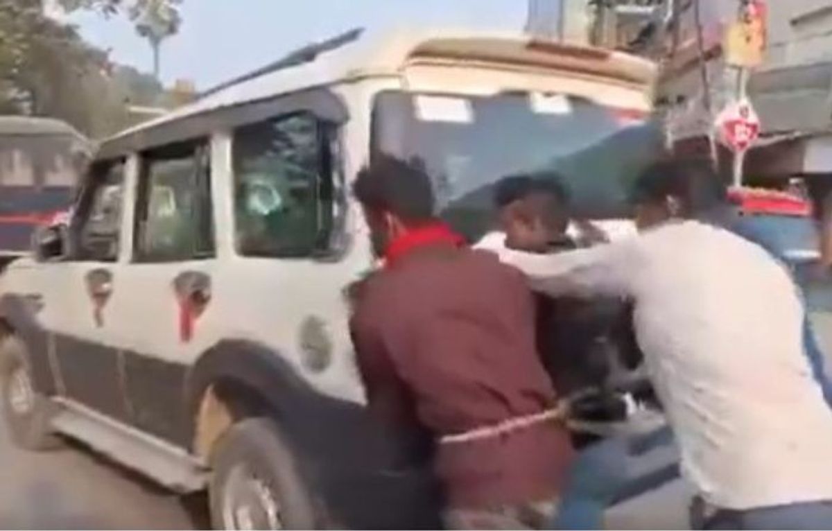 Four accused push a police car that ran out of fuel while taking them to court in the eastern Indian state of Bihar on February 4, 2024.