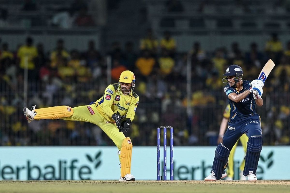Gujarat Titans' Shubman Gill (R) plays a shot as Chennai Super Kings' Mahendra Singh Dhoni gestures during the Indian Premier League 2023