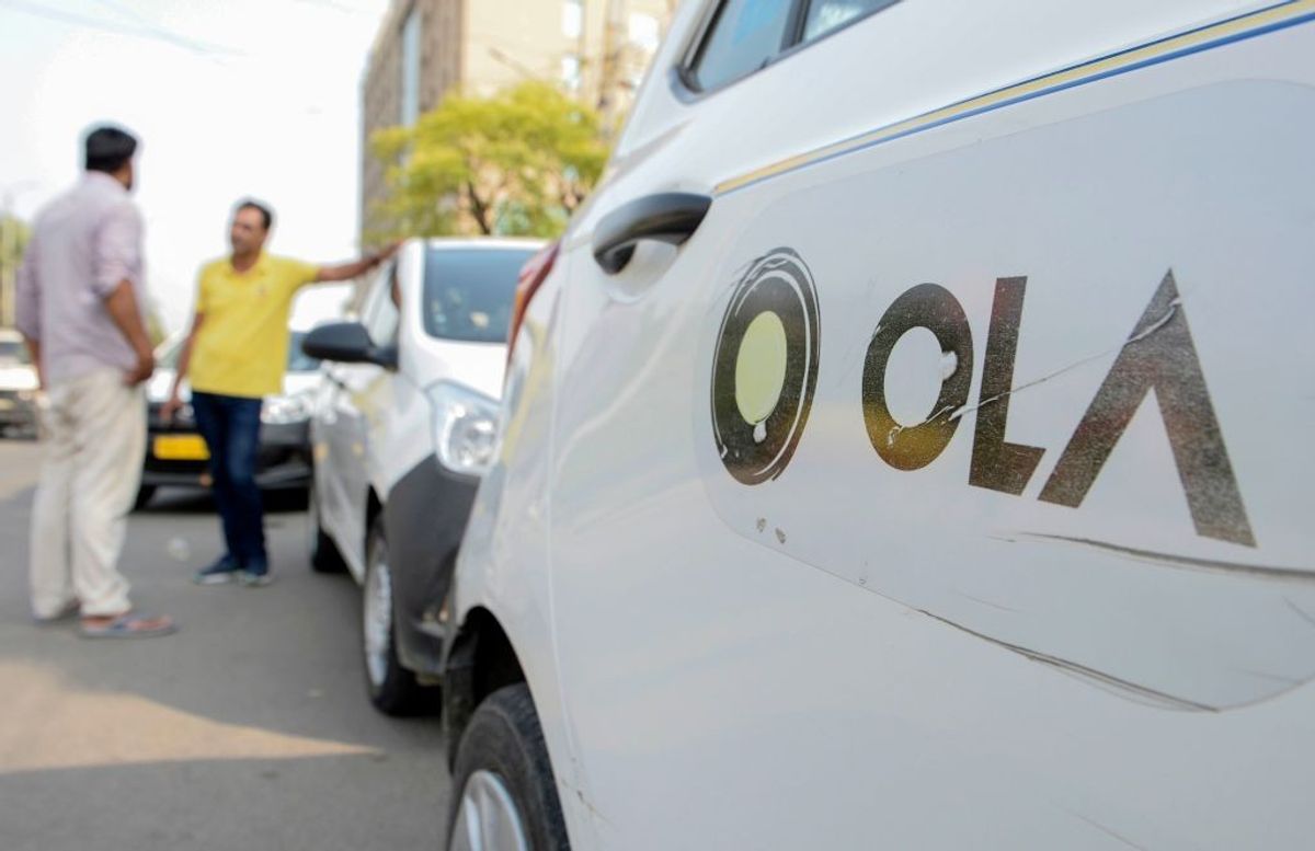 In this photograph taken on September 12, 2019, Ola cab drivers talk with each other as they wait for passengers by a roadside in Amritsar in India's Punjab.