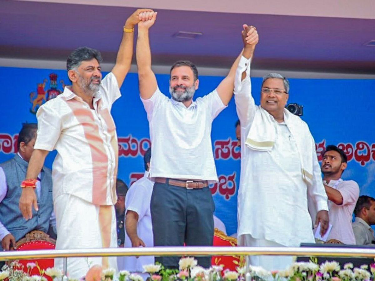 Indian Congress leader Rahul Gandhi )(c) holds hands with the new chief minister of the southern Indian state of Karnataka, Siddaramaiah (R), and deputy CM DK Shivakumar (L) celebrate during their swearing-in ceremony at Sree Kanteerava Stadium in state capital Bengaluru