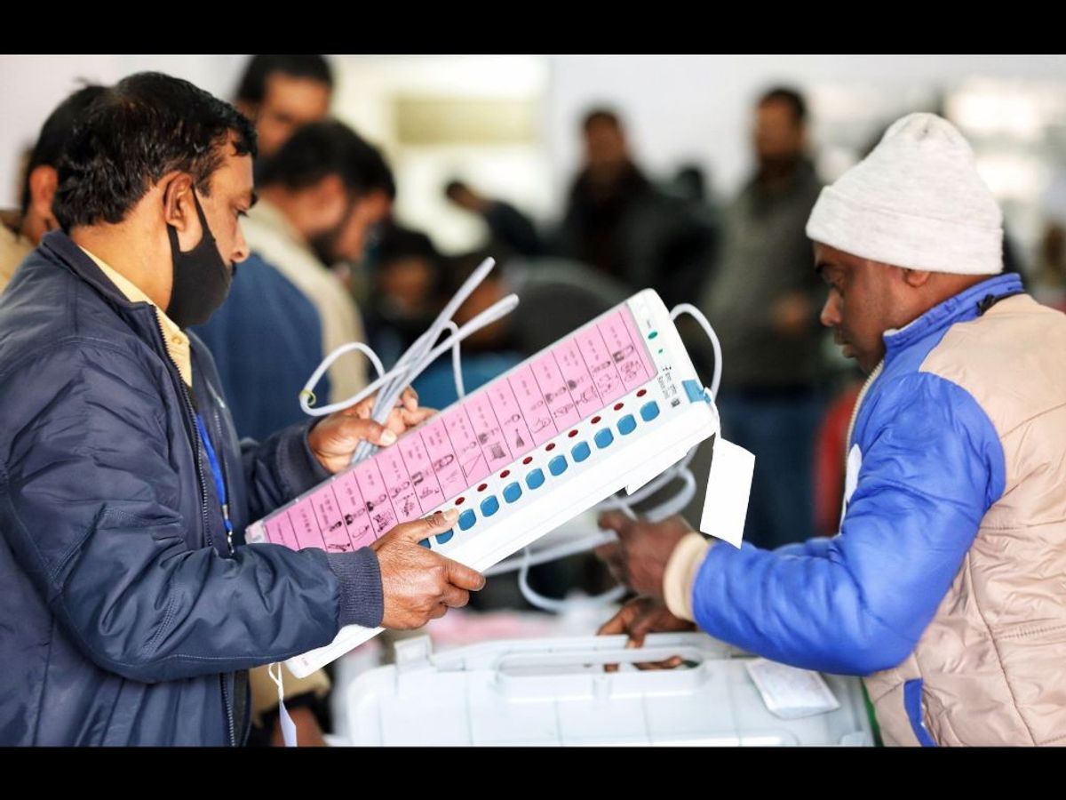 Indian polling officials check an electronic voting machine and voter-verified paper audit trail machine.