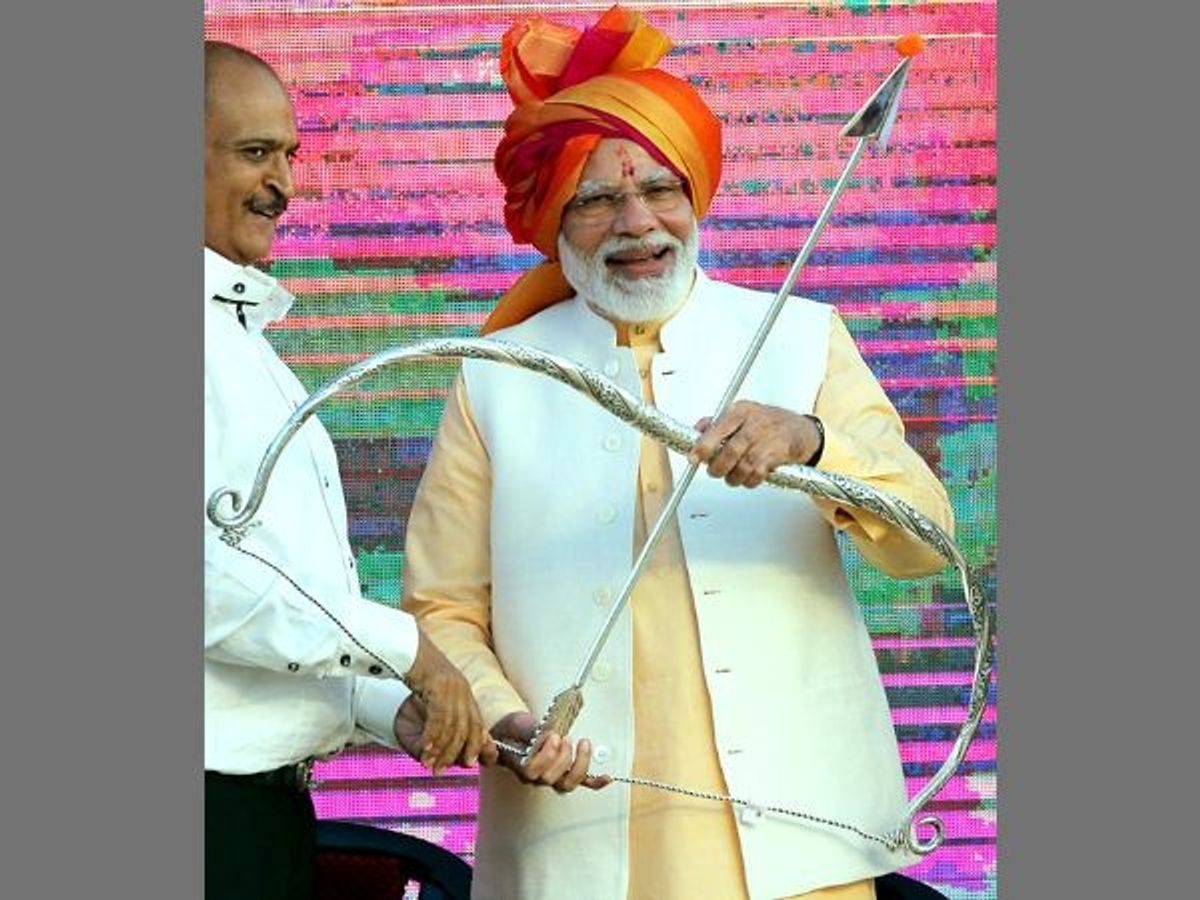 Indian prime minister Narendra Modi holds a bow and arrow at a public rally.