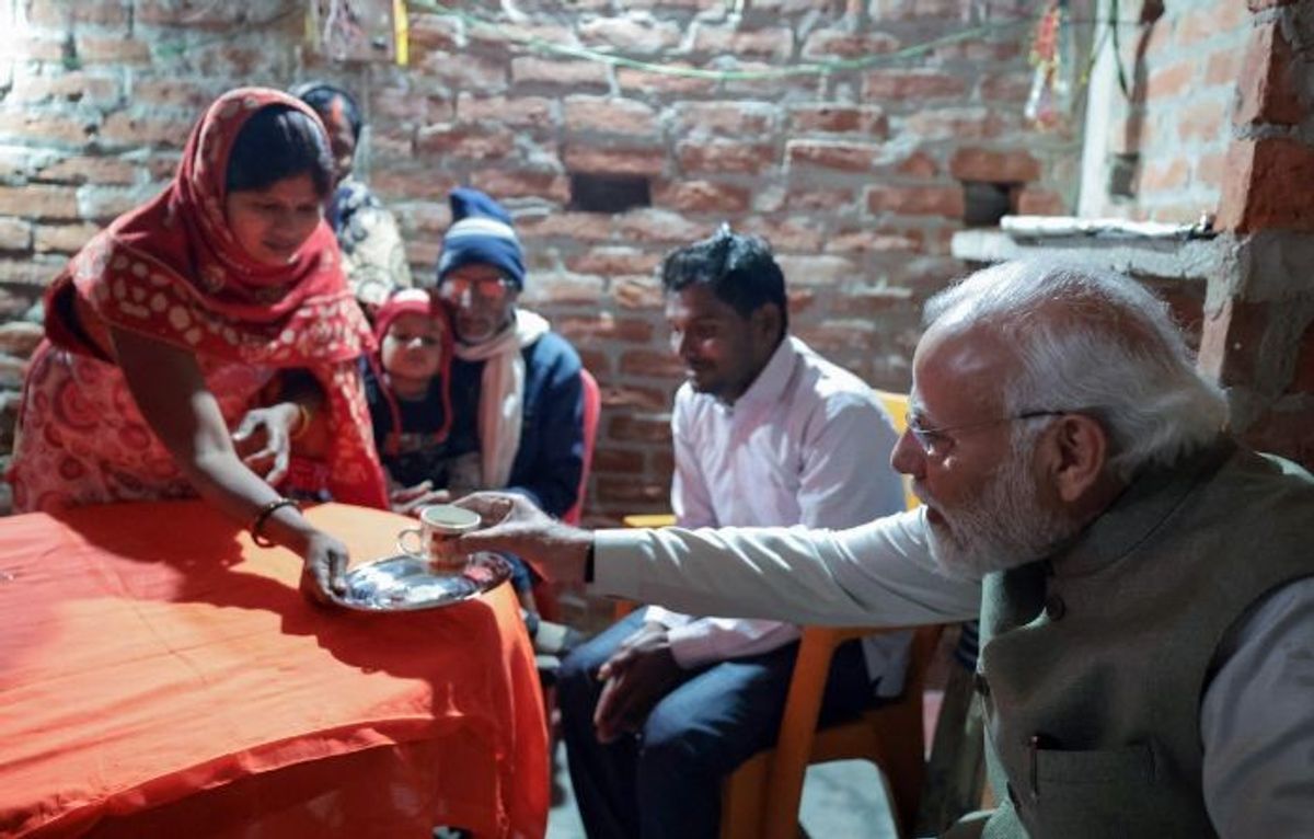Indian prime minister Narendra Modi takes tea at the house of Meera Manjhi, the 100 millionth beneficiary of Ujjwala Yojana cooking gas scheme, in Ayodhya in the northern state of Uttar Pradesh