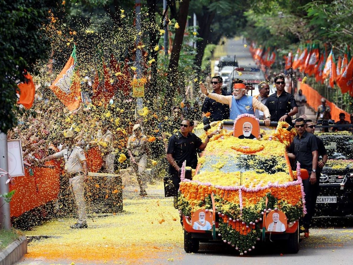 Indian prime minister Narendra Modi waves while being showered with flower petals by the supporters during a roadshow for the Karnataka Assembly elections in state capital Bengaluru