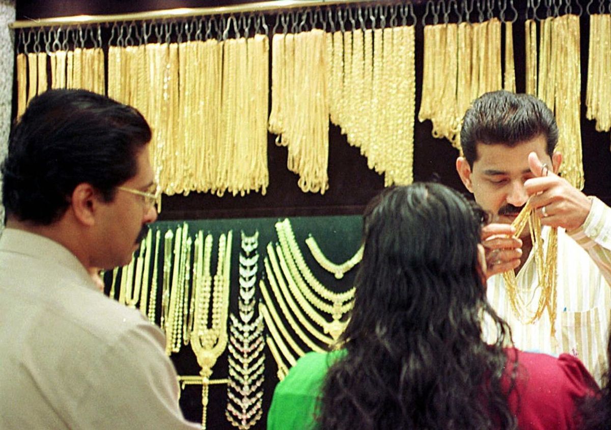 Indian shoppers look at the selection of gold chains, at a shop in Dubai, UAE