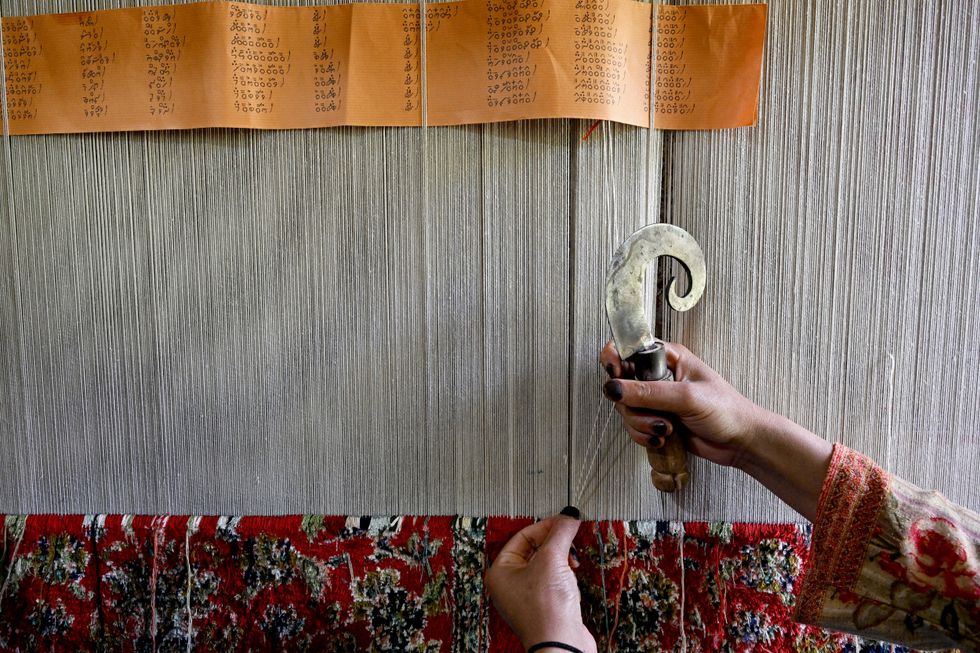 Kashmiri craftswoman weaves a silk carpet