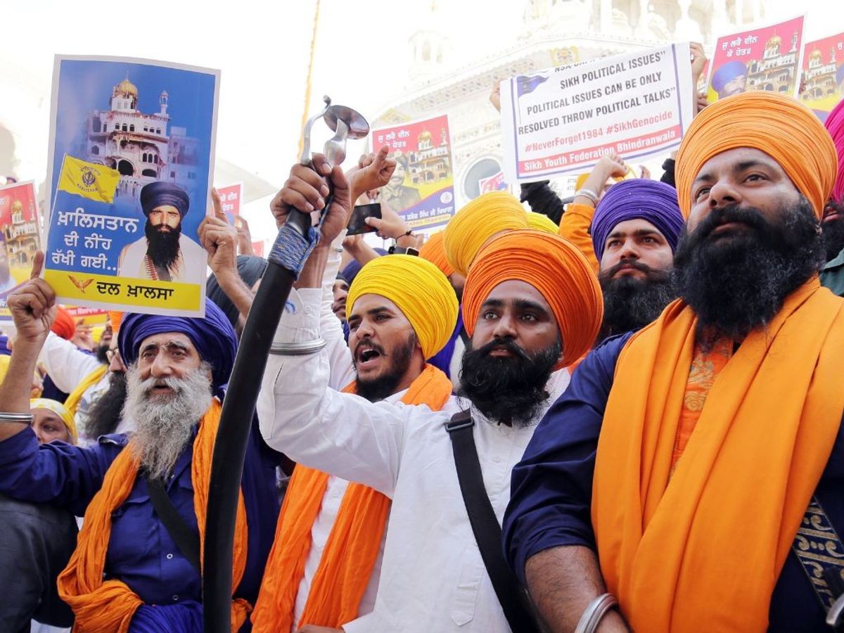 Members of the Sikh community raise slogans near the Akaal Takht Sahib building at the Golden Temple in the northern Indian state of Punjab