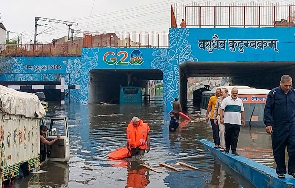 Passengers of a bus stranded in a flooded underpass in Delhi walk to safety on June 28, 2024.