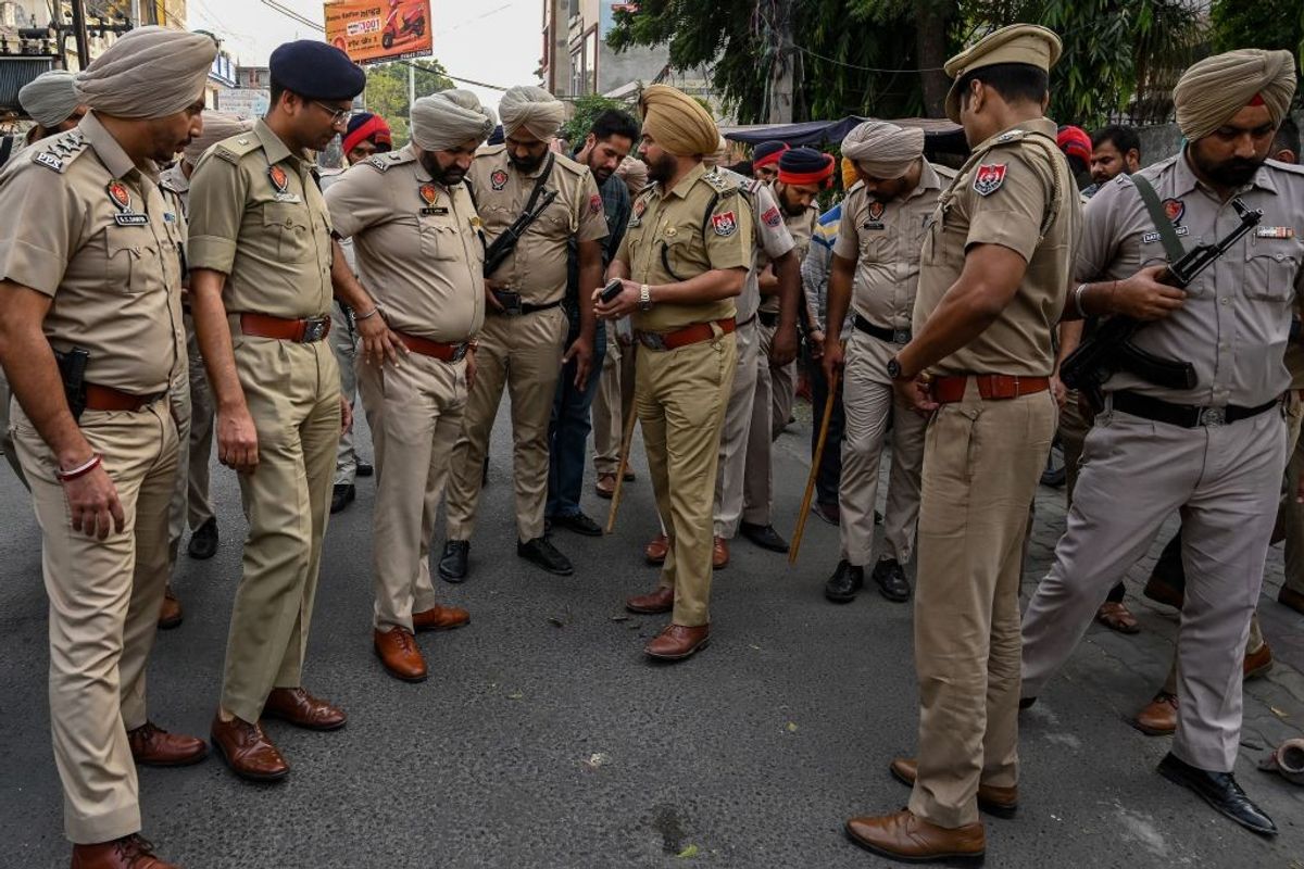 Police officers inspect Sudhir Suri's murder site