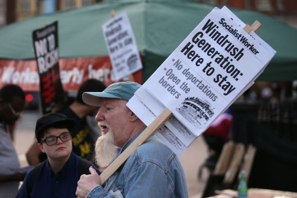 Supporters carry placards at the tail-end of a Windrush generation solidarity protest in Brixton, London on April 20, 2018.