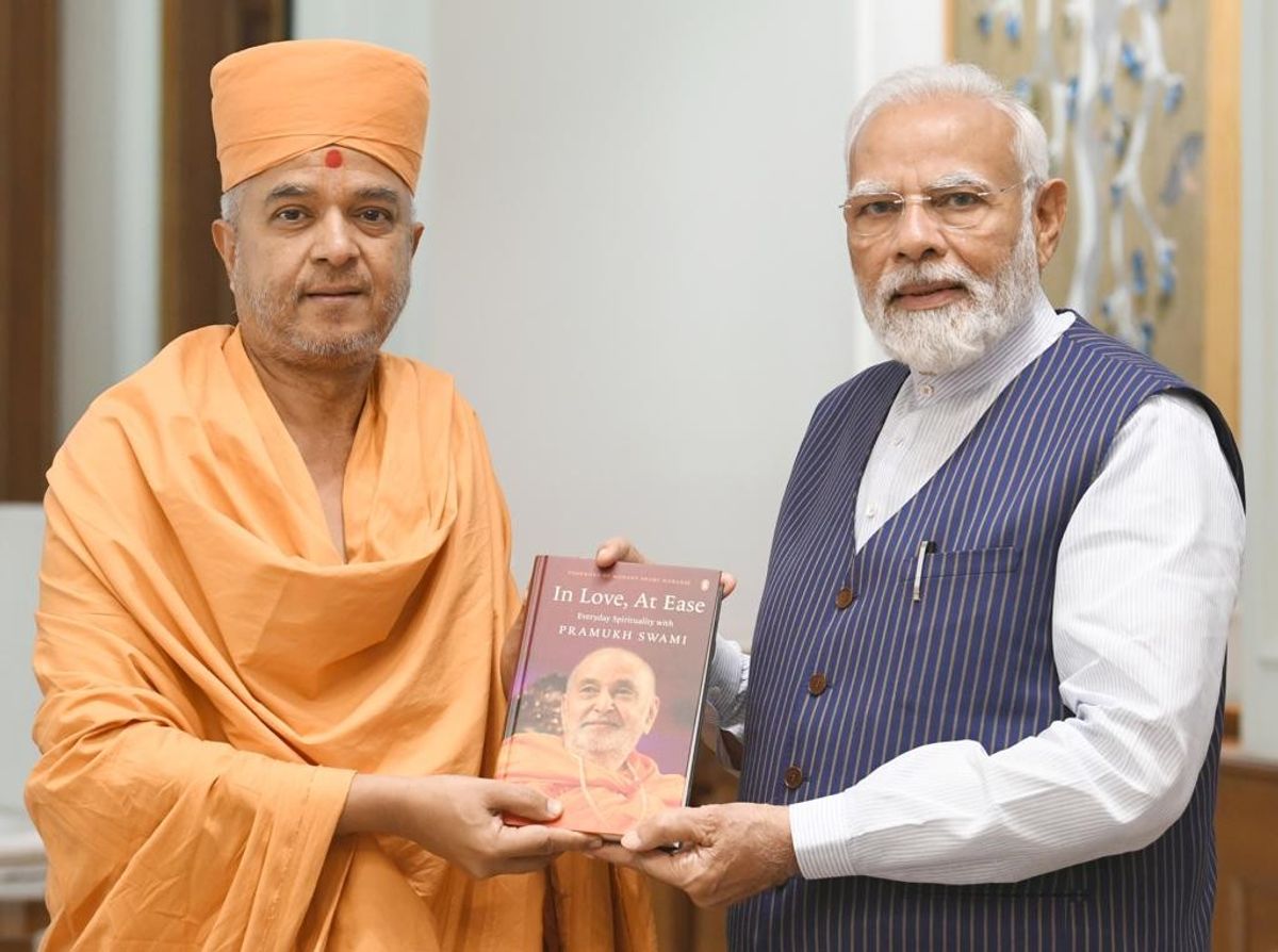 Swami Brahmaviharidas (L) presents prime minister Narendra Modi a copy of the book "In Love, At Ease: Everyday Spirituality with Pramukh Swami" in New Delhi
