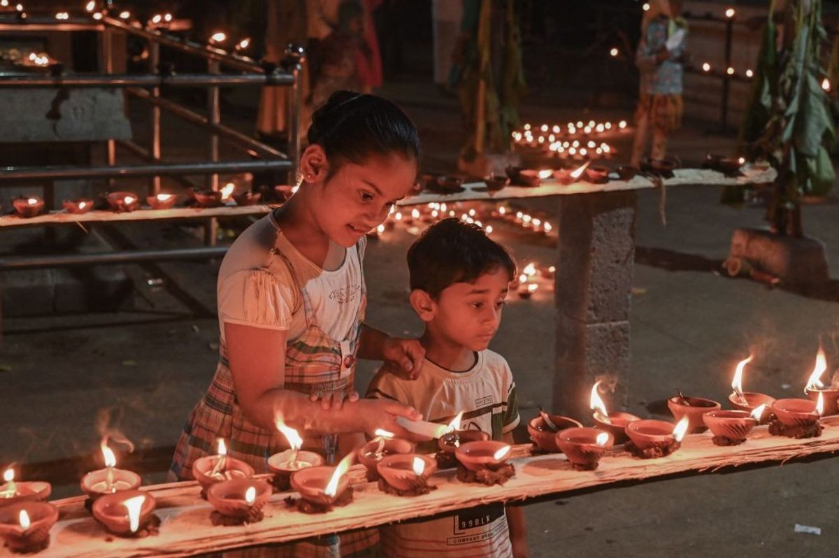 Two children light oil lamps during Diwali, the festival of light.