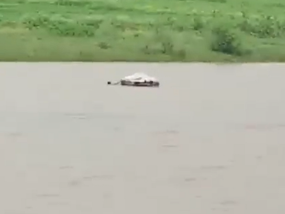 Villagers cross a flooded river with a man's corpse in India