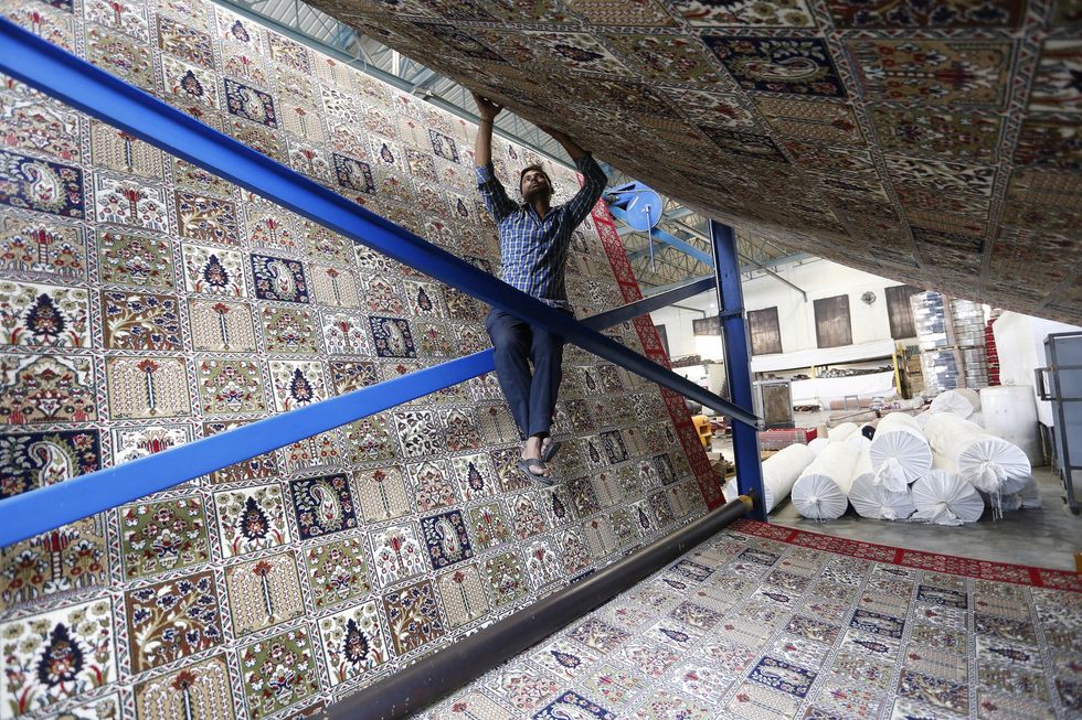 worker weaves a carpet