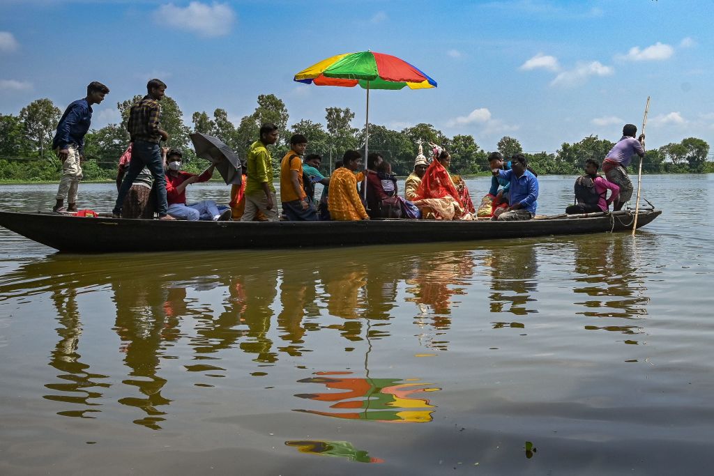 A newly married couple along with close family members return to their home on a boat in the flood hit city of Amta in Howrah district of West Bengal, about 65 kms from state capital Kolkata on August 5, 2021. (Photo by DIBYANGSHU SARKAR/AFP via Getty Images)