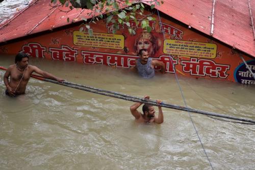 People take a dip outside a submerged Hanuman temple as the water levels of the Ganges and Yamuna rivers rise in Prayagraj, Uttar Pradesh, on August 7, 2021. (Photo by SANJAY KANOJIA/AFP via Getty Images)